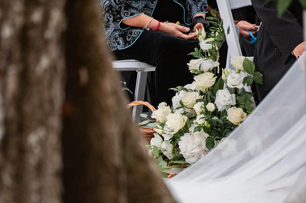 Roses blanches entre un arbre et le voile de la mariée - photo par Urielle Penn
