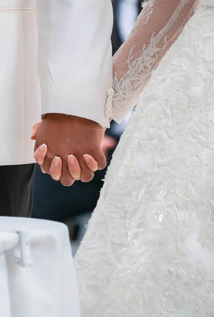 Les deux mains de mariés enlacées devant l'autel de la cérémonie - photo Urielle PENN photographe de mariage