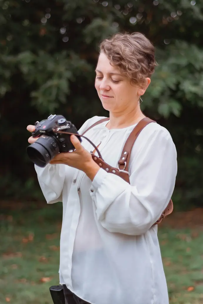 Photographe femme habillée en blanc qui regarde son appareil photo - photo Urielle PENN photographe de mariage