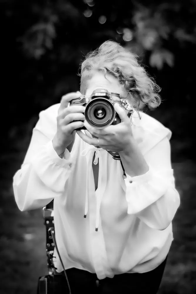 Femme photographe vêtue de blanc en train de prendre une photo - photo Urielle Penn photographe de mariage