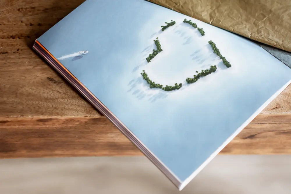 Album photo ouvert à la page d'une photo vue du ciel d'un îlot paradisiaque aux arbres en forme de cœur - photo Urielle Penn photographe de mariage